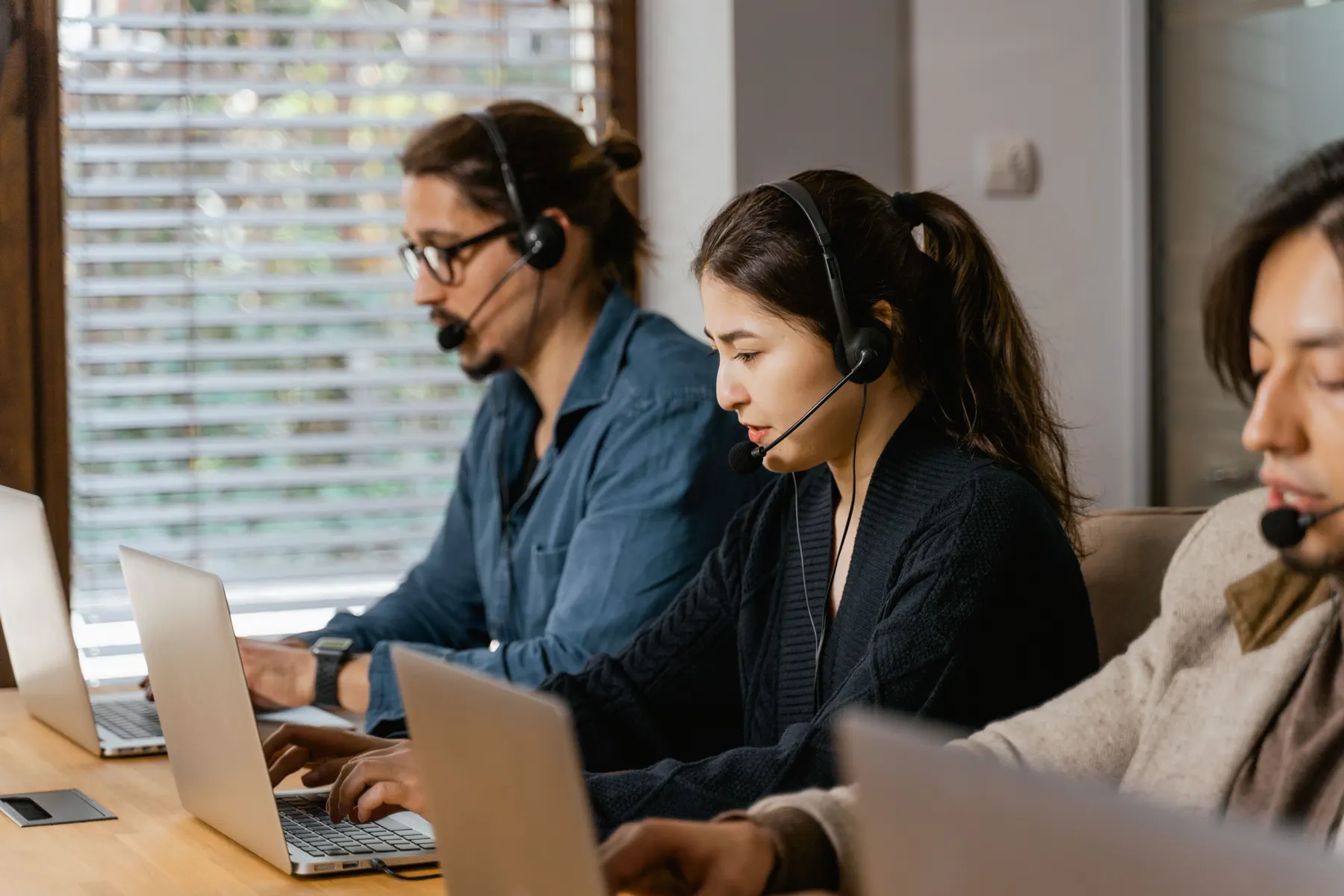 Support-Team mit Headsets arbeitet an Laptops